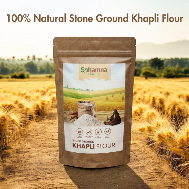 A stand-up pouch of Sohamna Organics Stone Ground Khapli Flour stands in the center of a golden wheat field. The packaging is brown with a white and green label.