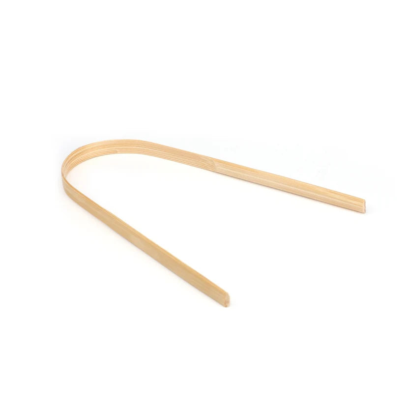 A single curved, thin wooden strip or paddle made of light natural wood, photographed on a seamless white background.