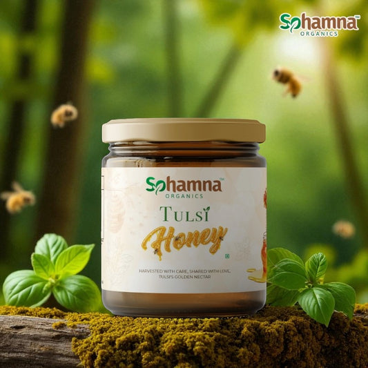 A jar of Sohamna Organics Tulsi Honey displayed on a mossy log with green leaves and flying bees against a soft green forest background.